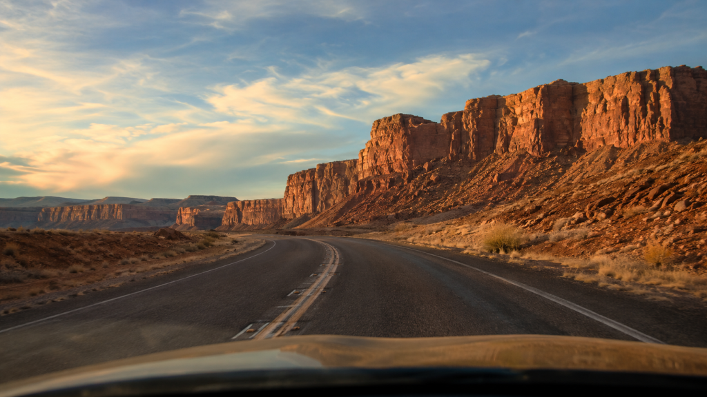 New Mexico desert road trip — scenic highway through red rock canyon at golden hour